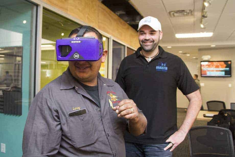 Customer using VR goggles while shopping for manufactured homes with Alberto Piña of Braustin Homes behind him.