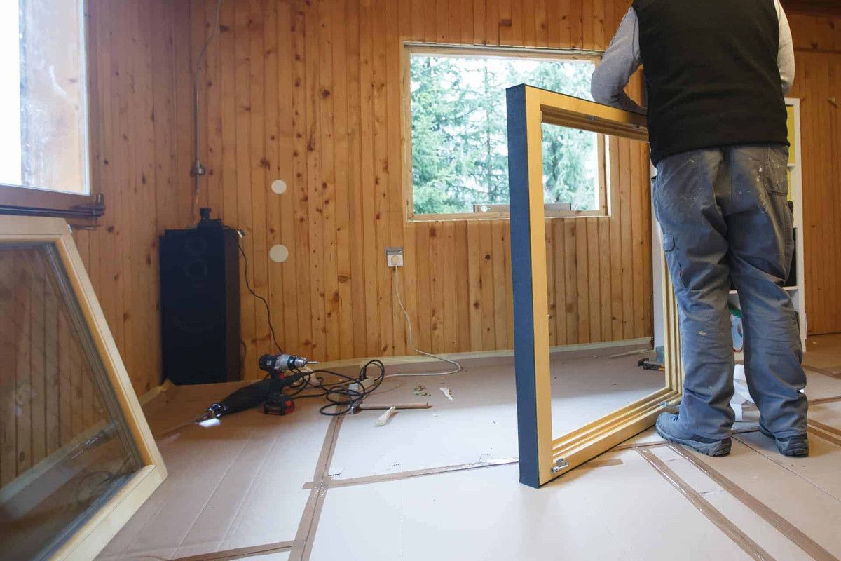 Man installing new window in an old mobile home.