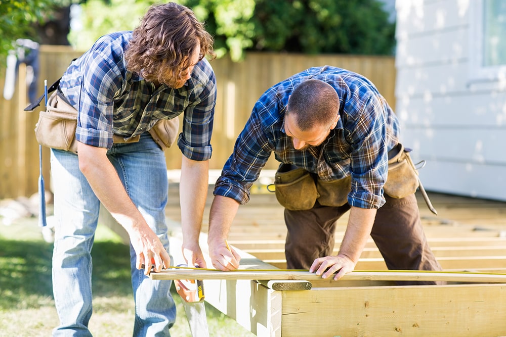 man and woman measuring wood to prepare mobile home for hurricane