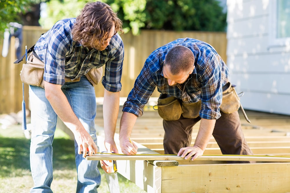 man and woman measuring wood to prepare mobile home for hurricane