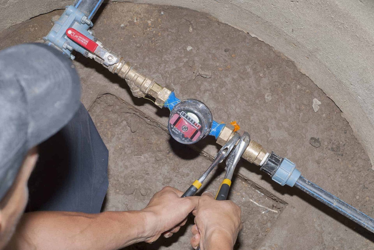 man holding wrenches and connects plumbing fittings