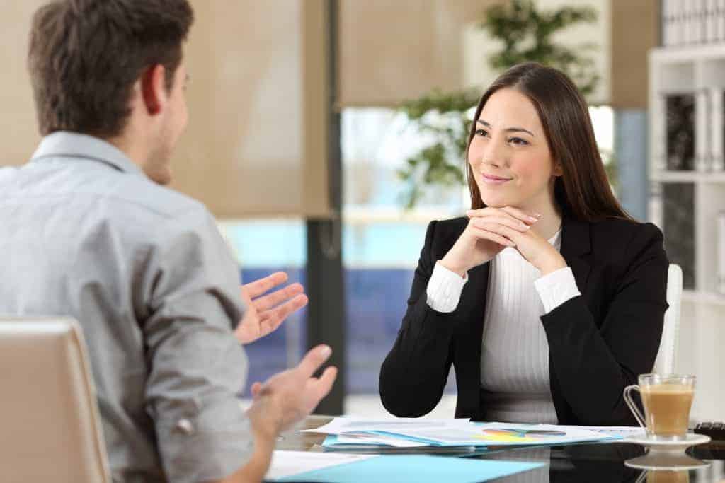 Woman looking at a man talking to one another across a table with charts laid out on the table