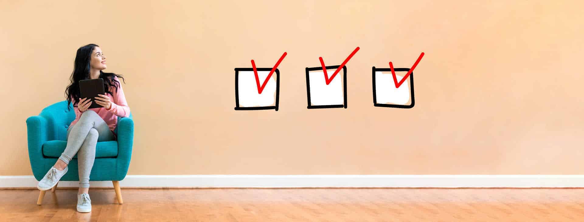 Checklist with young woman holding a tablet computer in a chair with three check boxes to the right