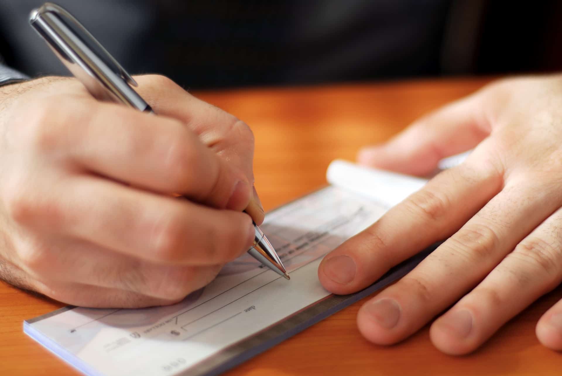 Closeup on man's hands writing a check