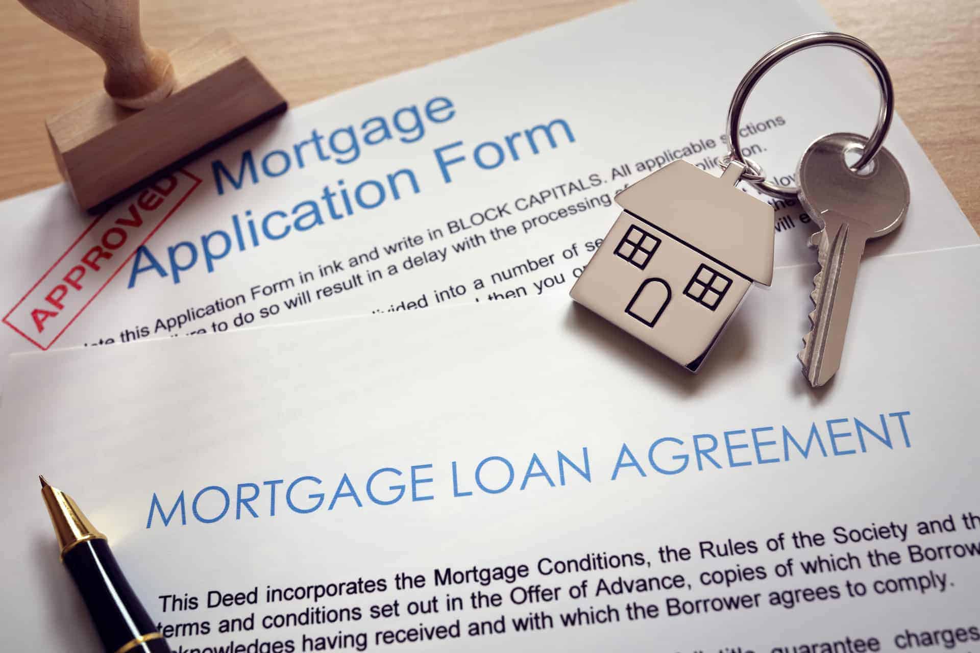 Approved Mortgage loan agreement application with key on house shaped keyring