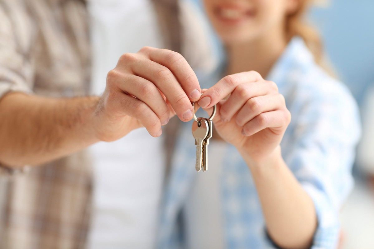 Young, and happy couple together hold a set of keys to their new home.