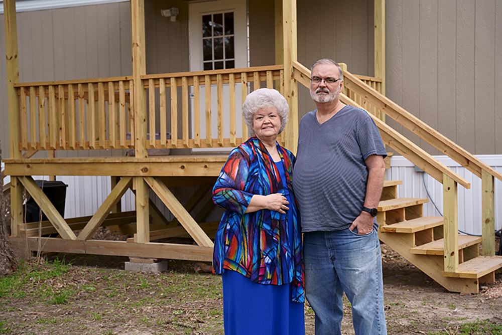 two elders standing in front of their mobile home